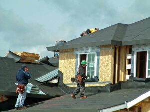 Metal, slate, tile, and asphalt roofing samples arranged beside a snow-dusted residential roof.